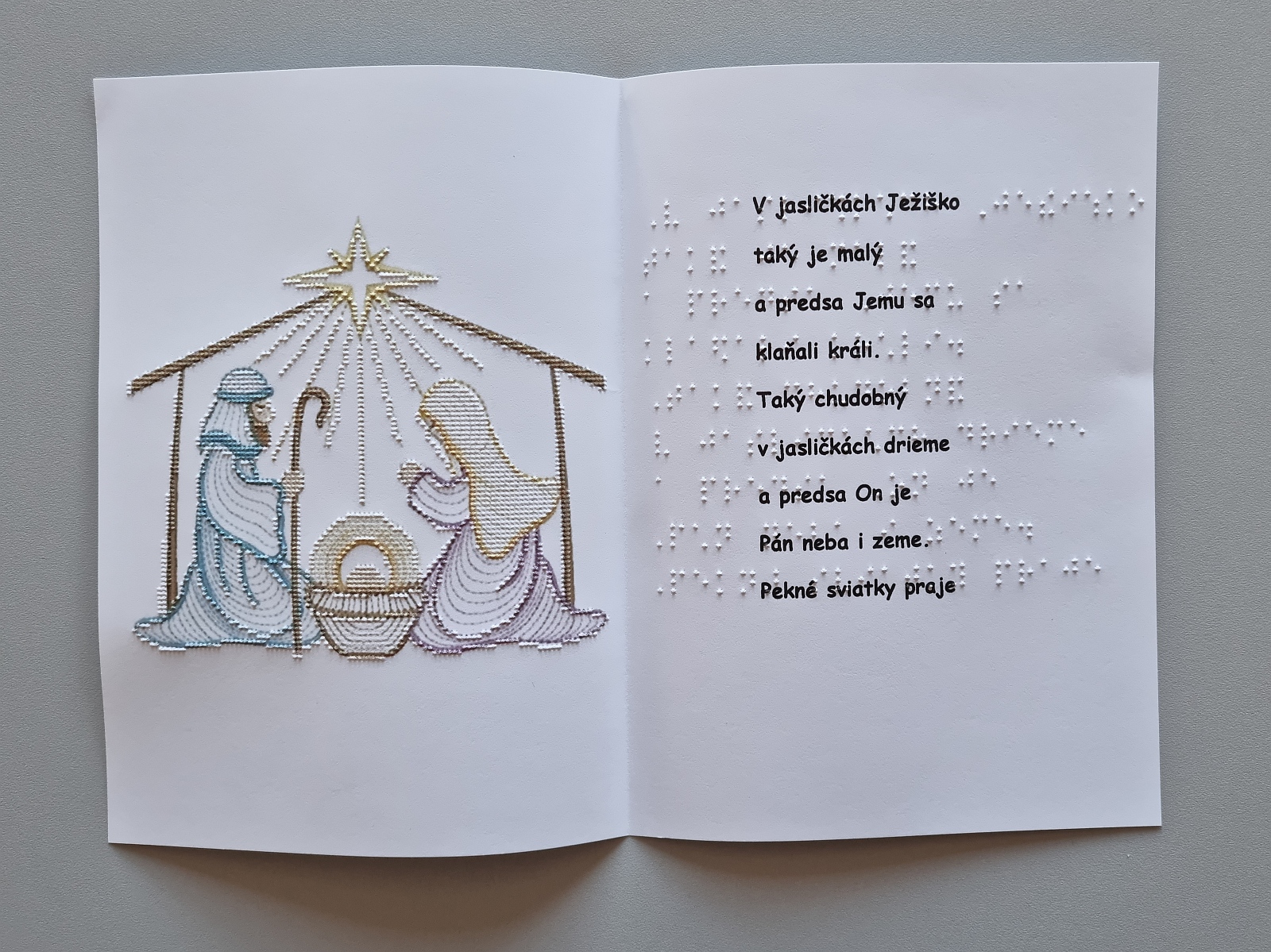 Vianočná pohľadnica, na farebnom obrázku sú vyobrazené jasličky s hviezdou. Text v braili aj čiernotlači.