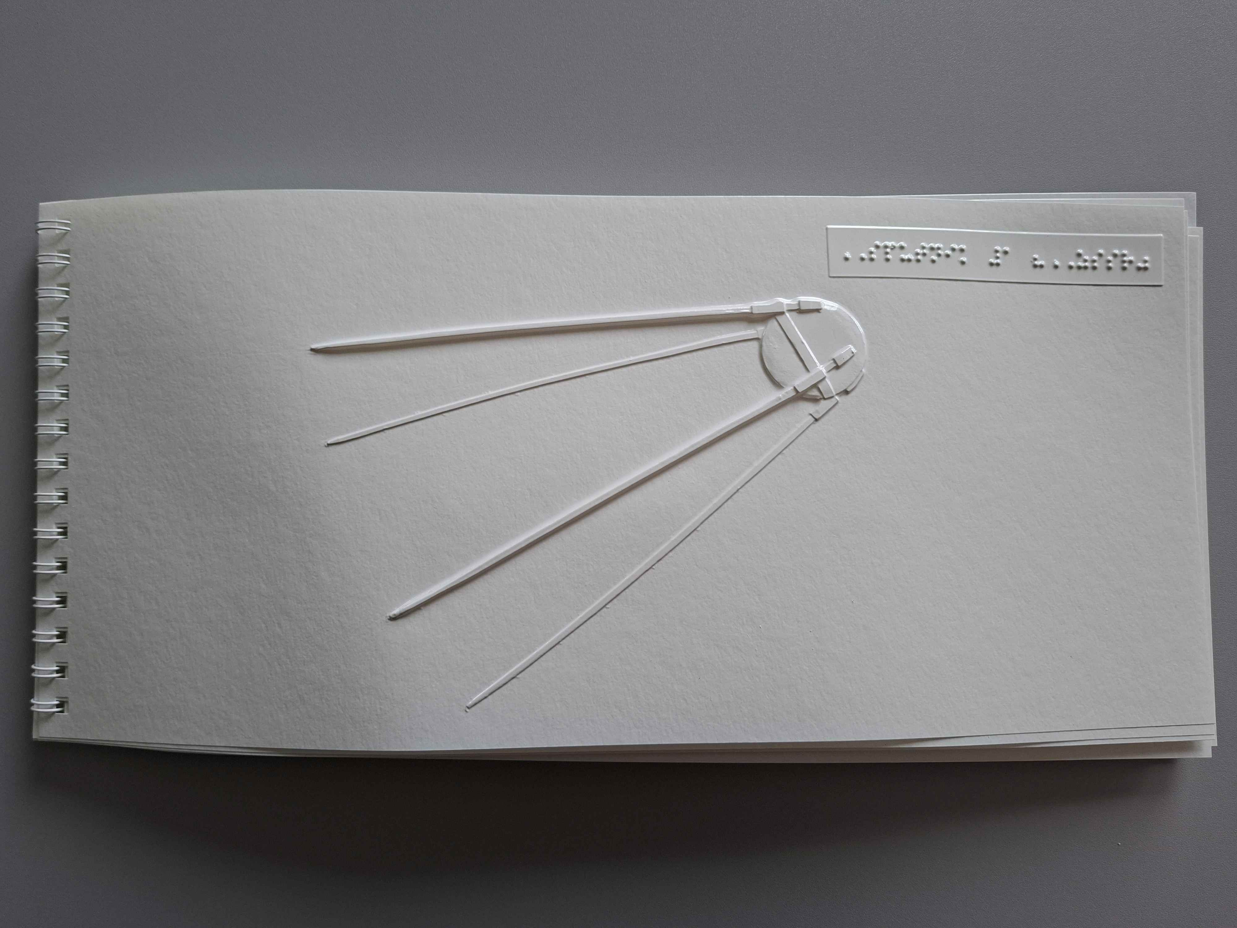 Biely list s reliéfnym obrázkom družice ((malé telo pri jednom konci a z neho vychádzajú dlhé ramená